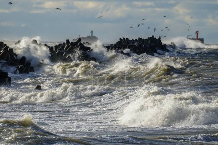 Coastal storm in the Baltic Sea, big waves crash against the concrete breakwater at the port entrance