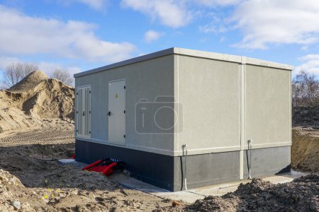 Unfinished modern large outdoor electric high voltage power distribution box in a new industrial facility, new transformer building