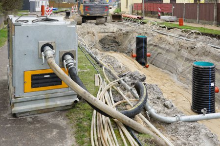 Téléchargez les photos : Grande pompe à eau diesel portable pour l'assèchement de la tranchée souterraine profonde de remplacement de pipeline dans la rue de la ville - en image libre de droit