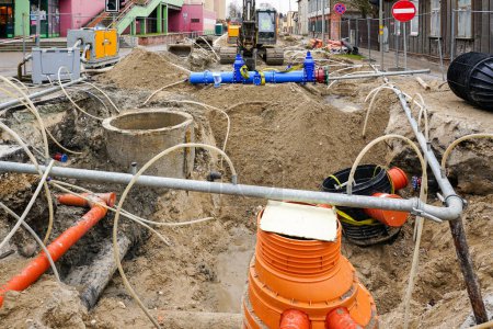 Téléchargez les photos : Fosse souterraine de remplacement de tuyaux sur la rue de la ville, système d'assèchement du site, nouveau pipeline avec vannes à vanne - en image libre de droit