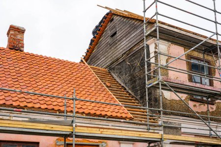 Téléchargez les photos : Réparation de la façade et du toit d'une maison historique, remplacement des tuiles d'argile, restauration de la façade en plâtre, treillis en bois sous stuc - en image libre de droit