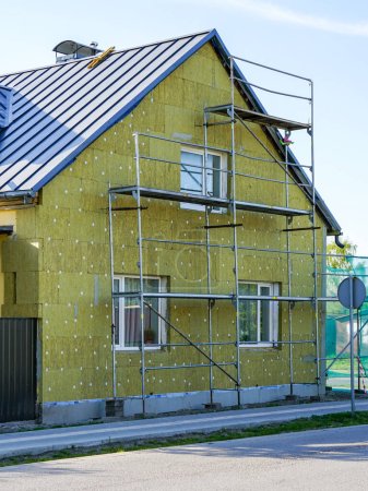 Foto de Aislamiento térmico de la fachada de la casa residencial con gruesas losas de lana mineral de roca utilizando andamios - Imagen libre de derechos