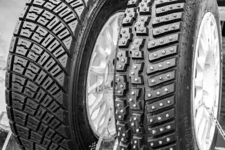 Photo for Two types of modern rally tires, studded winter snow and ice tire with big studs and asymmetric gravel tire - Royalty Free Image