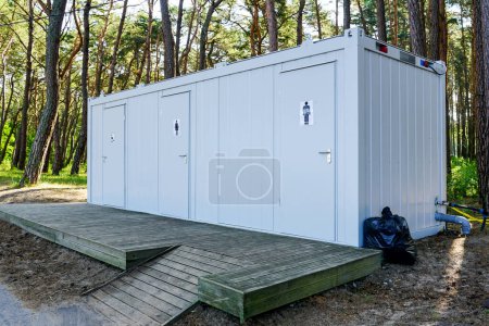 Téléchargez les photos : Conteneur moderne à trois toilettes en métal public avec terrasse en bois dans un parc en bord de mer, amélioration de l'environnement - en image libre de droit