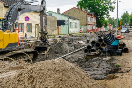 Téléchargez les photos : Vue de reconstruction de rue avec tranchée profonde, tuyaux souterrains anciens et nouveaux, nouveau puits vertical en plastique - en image libre de droit
