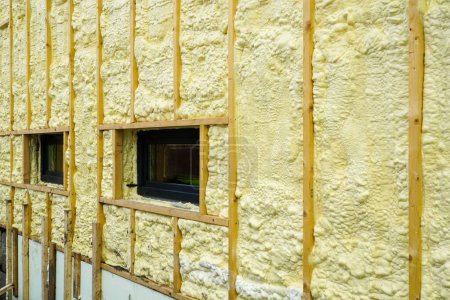 Photo for The facade of the residential house sprayed with a layer of polyurethane thermal insulation foam before siding with wooden planks - Royalty Free Image