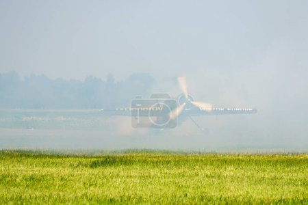 Photo for Liepaja, Latvia - August 06, 2023 - Aerobatic Lithuanian pilot Jurgis Kairys with his Sukhoi SU-31 aeroplane on the runway in a cloud of smoke - Royalty Free Image