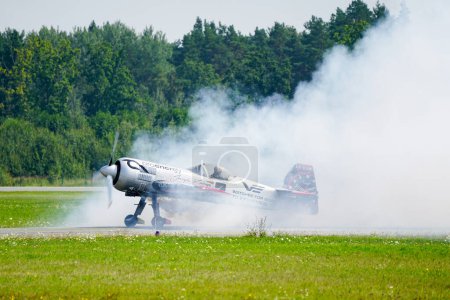 Photo for Liepaja, Latvia - August 06, 2023 - Aerobatic Lithuanian pilot Jurgis Kairys with his Sukhoi SU-31 aeroplane on the runway in a cloud of smoke - Royalty Free Image