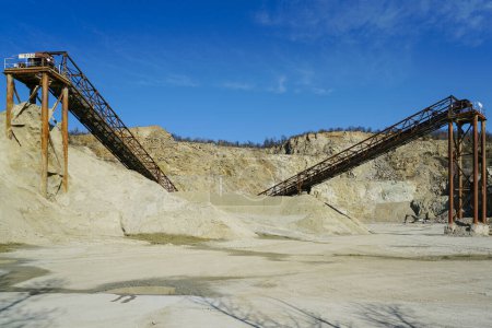 Grandes structures métalliques rouillées pour transporter des roches dans une carrière minière de dolomite, concassage de gravier, tri, transport, fond bleu ciel