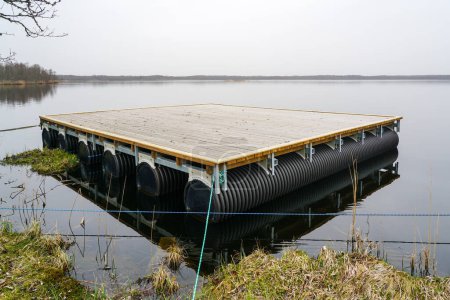A new empty floating wooden platform on pontoons in the lake for the creation of a holiday and fishing house on the water