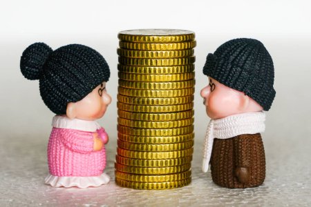 Hoher Stapel gelber Münzen zwischen Spielzeugfiguren älterer Männer und Frauen, Konzept für Geldstreitigkeiten, Konzept für finanzielle Unstimmigkeiten