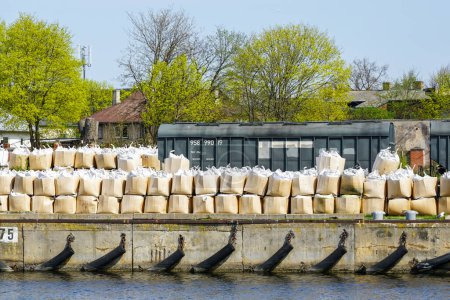 Grandes fardos de fertilizantes minerales se apilan en la orilla del canal del puerto antes de ser cargados en un barco