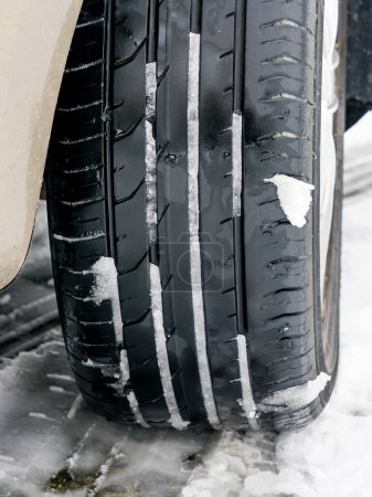 Summer tread car tire in the snow, driving with tires unsuitable for the season, unsafe and dangerous traffic, summer tread tire on slippery snow road