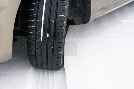 Rueda de coche con neumático de pisada de verano inseguro durante la conducción a través de carretera de nieve resbaladiza en la temporada de invierno, neumáticos de verano en la nieve