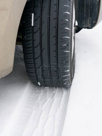 Car wheel with unsafe summer tread tire during driving through slippery snow road at winter season, summer tires in snow