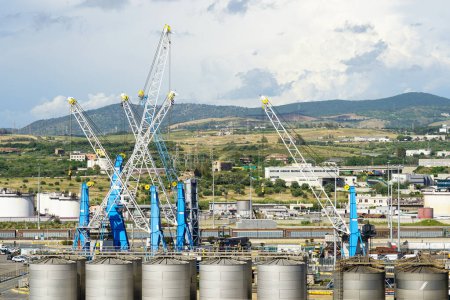 Industrielle Hafenlandschaft Civitavecchia mit vielen Kränen, Chemikalienlagertanks auf bergigem Naturhintergrund
