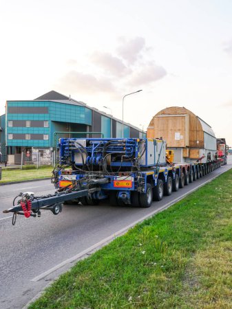 Very long specialized multi axle truck trailer carries very heavy oversize transmission network static synchronous compensator, rear view
