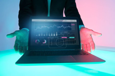Technologies commerciales modernes. Les mains d'un analyste d'affaires masculin démontrent des indicateurs reflétant la dynamique des affaires sur un ordinateur portable.