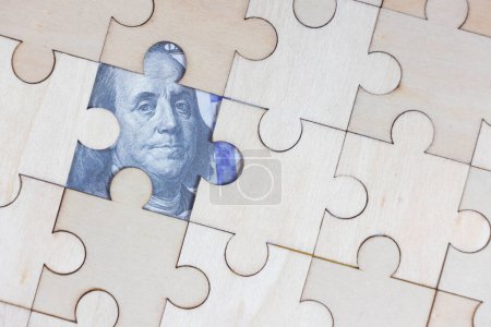 Téléchargez les photos : Le puzzle en bois a un écart avec des billets de dollar en dessous. - en image libre de droit