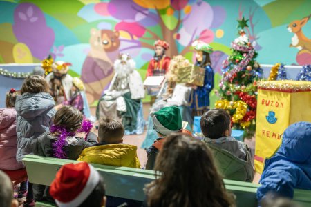 Photo for The three kings visiting children in a children's school, christian tradition, christmas festival in school, unrecognizable people, the background out of focus. - Royalty Free Image