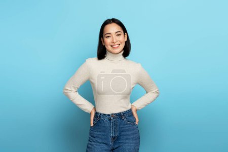 Photo for Portrait of pretty smiling happy woman looking at camera with cute positive face, being in good mood. Indoor studio shot isolated on blue background - Royalty Free Image