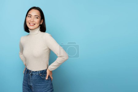 Photo for Smiling happy woman looking away with cute positive face, being in good mood. Indoor studio shot isolated on blue background - Royalty Free Image