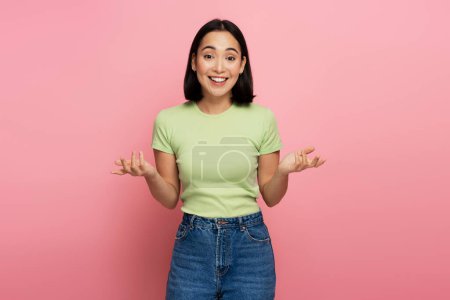Photo for Uncertain positive woman with raised arms, dont know what to do. Indoor studio shot isolated on pink background - Royalty Free Image