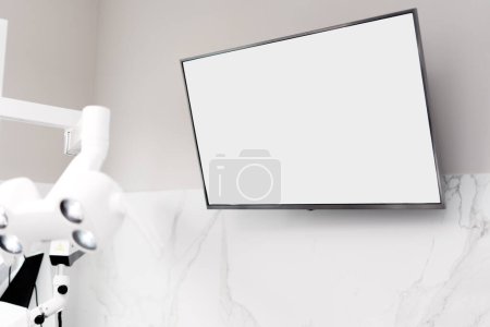Téléchargez les photos : Un écran vierge est accroché au mur d'un cabinet dentaire. Lieu de publicité, espace de copie. - en image libre de droit