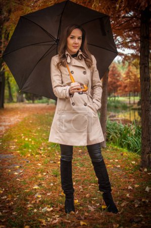 Photo for Young girl in coat in forest. Fashion woman in coat in park. Slim young fashion model wearing white coat outdoor. Beautiful woman in leopard coat with umbrella in the autumn park - Royalty Free Image