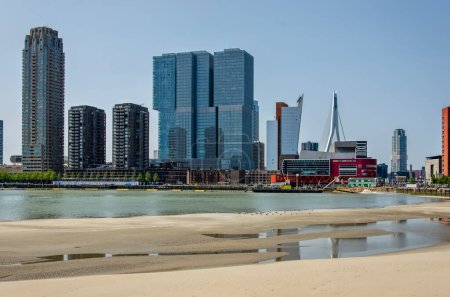 Téléchargez les photos : Rotterdam, Pays-Bas, 5 juin 2023 : les tours de la jetée Wilhelmina se reflètent dans les flaques d'eau sur la plage temporaire du projet de remise en état des terres de Rijnhaven - en image libre de droit