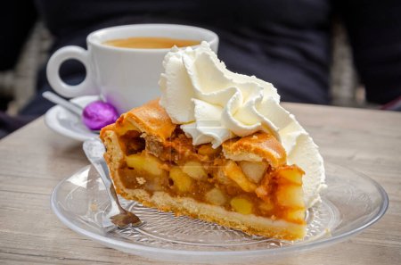 Photo for Apple pie with whipped cream on a terrace, as well as a cup of coffee with a purple easter egg - Royalty Free Image