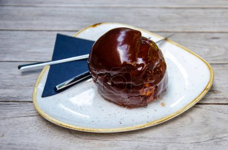 Téléchargez les photos : Un Bossche Bol, casse-croûte signature de la ville de Den Bosch, Pays-Bas, avec crème fouettée à l'intérieur d'une boule recouverte de chocolat, à manger avec un couteau et une fourchette - en image libre de droit