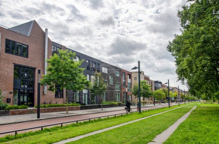 Foto de Enschede, Países Bajos, 9 de agosto de 2023: larga fachada con edificios residenciales a lo largo del eje central en el barrio reconstruido Roombeek - Imagen libre de derechos
