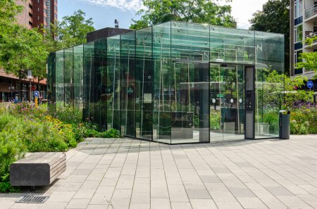 Foto de Enschede, Países Bajos, 9 de agosto de 2023: fachadas de vidrio de la entrada al aparcamiento debajo de la plaza Koningsplein, rodeado de mucha vegetación - Imagen libre de derechos