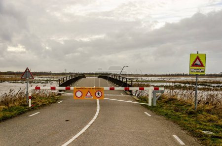 Photo for Werkendam, The Netherlands, December 29, 2024: barrier preventing access to bridge because of flooding as part of the Room for the river project in Noordwaard region in Biesbosch national park - Royalty Free Image