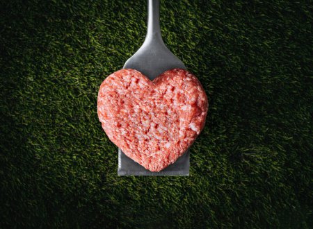 Photo for Heart shaped beef burger patty on a grilled spatula. dark background place for text. valentines day celebration concept - Royalty Free Image