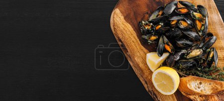 Photo for Fresh mussels in a wooden plate with herbs and lemon - Royalty Free Image