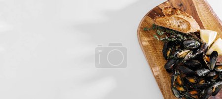 Foto de Fresh mussels in a wooden plate with herbs and lemon - Imagen libre de derechos