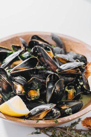Foto de Boiled mussels with parsley, spinach, Asian herbs and lemon and toasted baguette - Imagen libre de derechos
