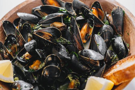 Foto de Boiled mussels with parsley, spinach, Asian herbs and lemon and toasted baguette - Imagen libre de derechos