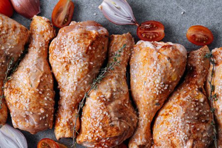 Téléchargez les photos : Pilons de poulet aux épices, paprika et graines de sésame, prêts à cuire sur une plaque à pâtisserie - en image libre de droit