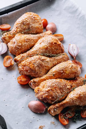 Photo for Chicken drumsticks with spices, paprika and sesame seeds, ready to bake on a baking sheet - Royalty Free Image