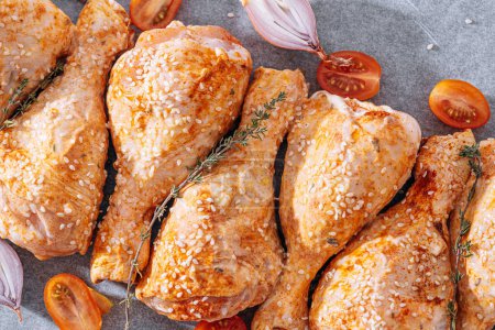 Téléchargez les photos : Chicken drumsticks with spices, paprika and sesame seeds, ready to bake on a baking sheet - en image libre de droit