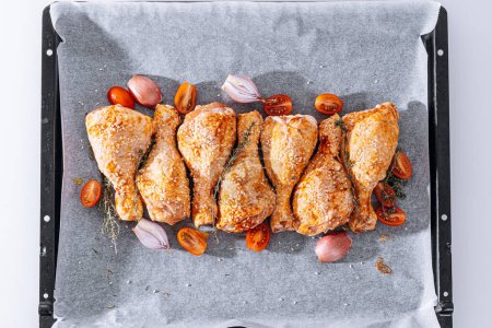 Téléchargez les photos : Pilons de poulet aux épices, paprika et graines de sésame, prêts à cuire sur une plaque à pâtisserie - en image libre de droit