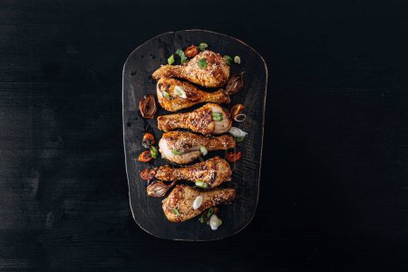 Téléchargez les photos : Pilons de poulet cuits au four avec sésame, miel et sauce soja, oignon et épices - en image libre de droit