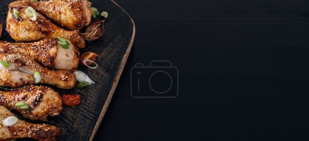 Téléchargez les photos : Pilons de poulet cuits au four avec sésame, miel et sauce soja, oignon et épices - en image libre de droit