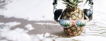 Photo for Fresh juicy ripe pineapple in sunglasses on the sand under the hot sun - Royalty Free Image