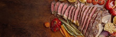 Téléchargez les photos : Steak de bœuf marbré sur l'os cuit à un état de grill moyen rare. à côté du steak, légumes grillés servant de plat d'accompagnement. charmant dîner de gala pour deux - en image libre de droit
