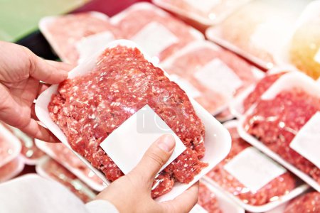 Buyer woman chooses minced meat in shop