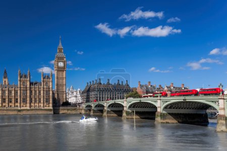 Photo for Big Ben with red buses on bridge over Thames river with boat in London, England, UK - Royalty Free Image